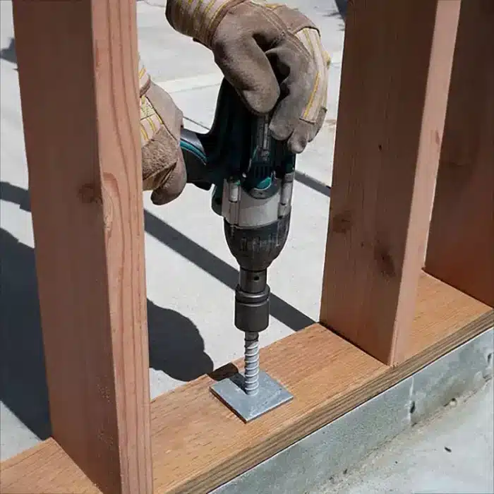 Photo of concrete screw being drilled into concrete through a wood frame